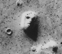 A satellite photo of a mesa in Cydonia, often called the Face on Mars. Later imagery from other angles did not contain the illusion. Image from Wiki.